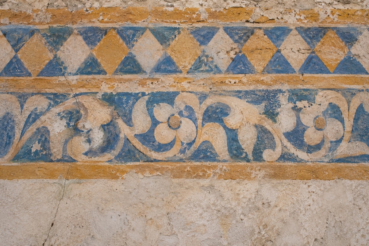 Weathered blue and ochre geometric and floral plaster patterns